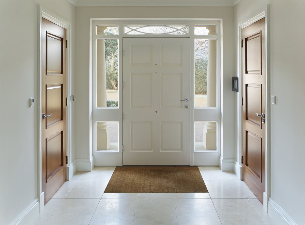 Recibidor con puertas de madera a los lados y puerta de entrada blanca acristalada